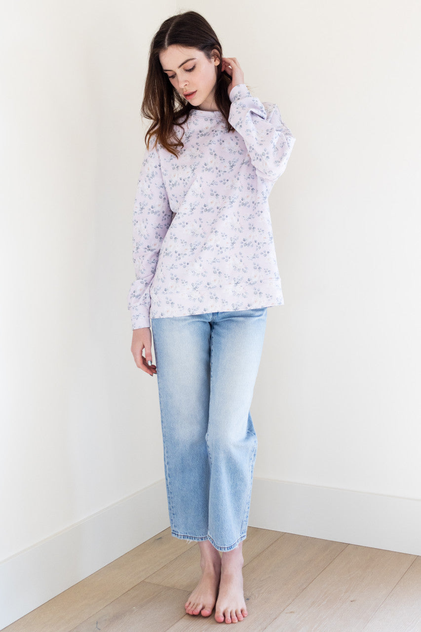 This soft lilac coloured long sleeve crew neck sweater has a white rose print pattern and ribbing details, giving it a stylish and feminine touch. It has a slightly boxy fit, making it comfortable and easy to wear for any casual occasion.